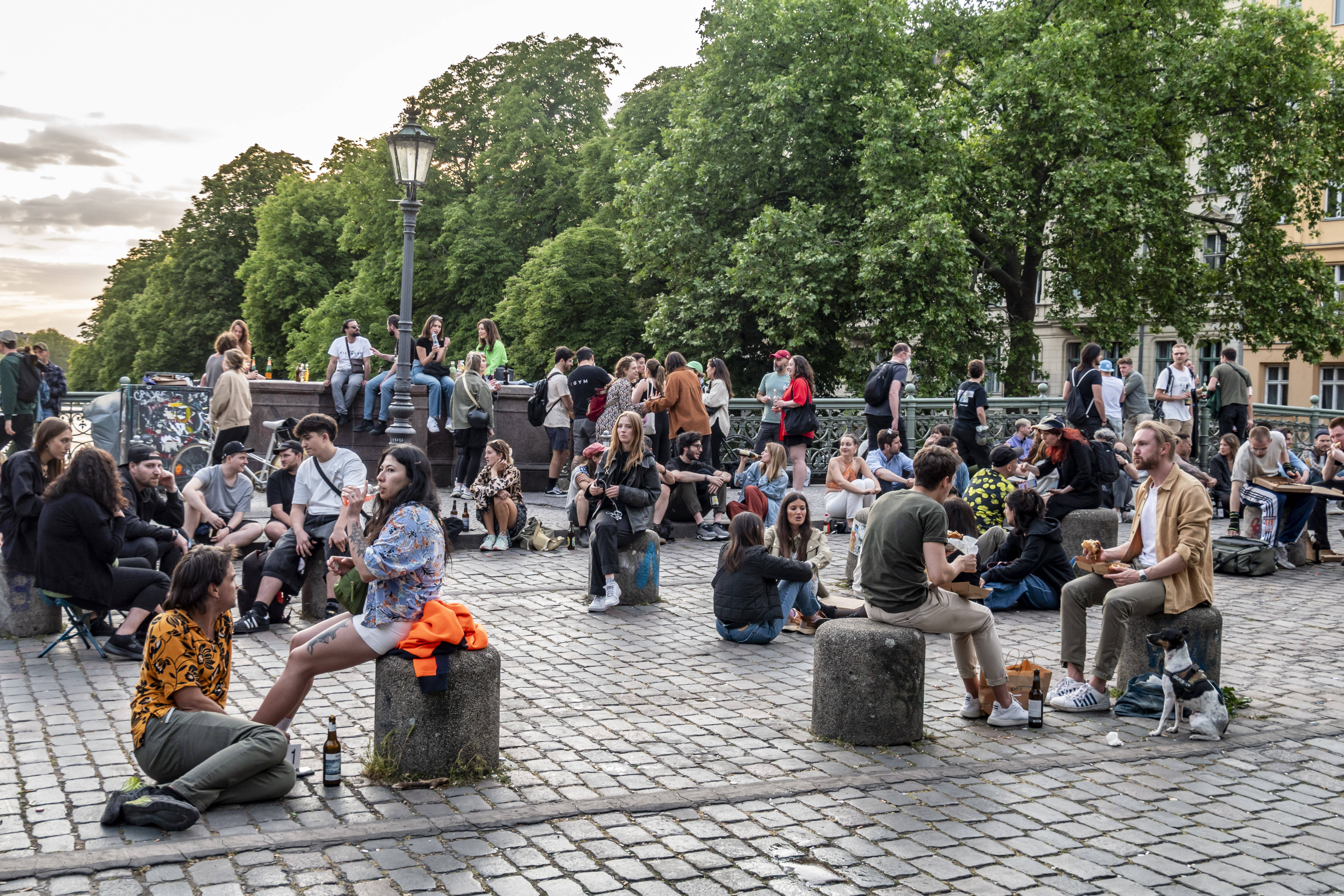 Junge Menschen sitzen auf der Admiralsbrücke in Berlin-Kreuzberg.