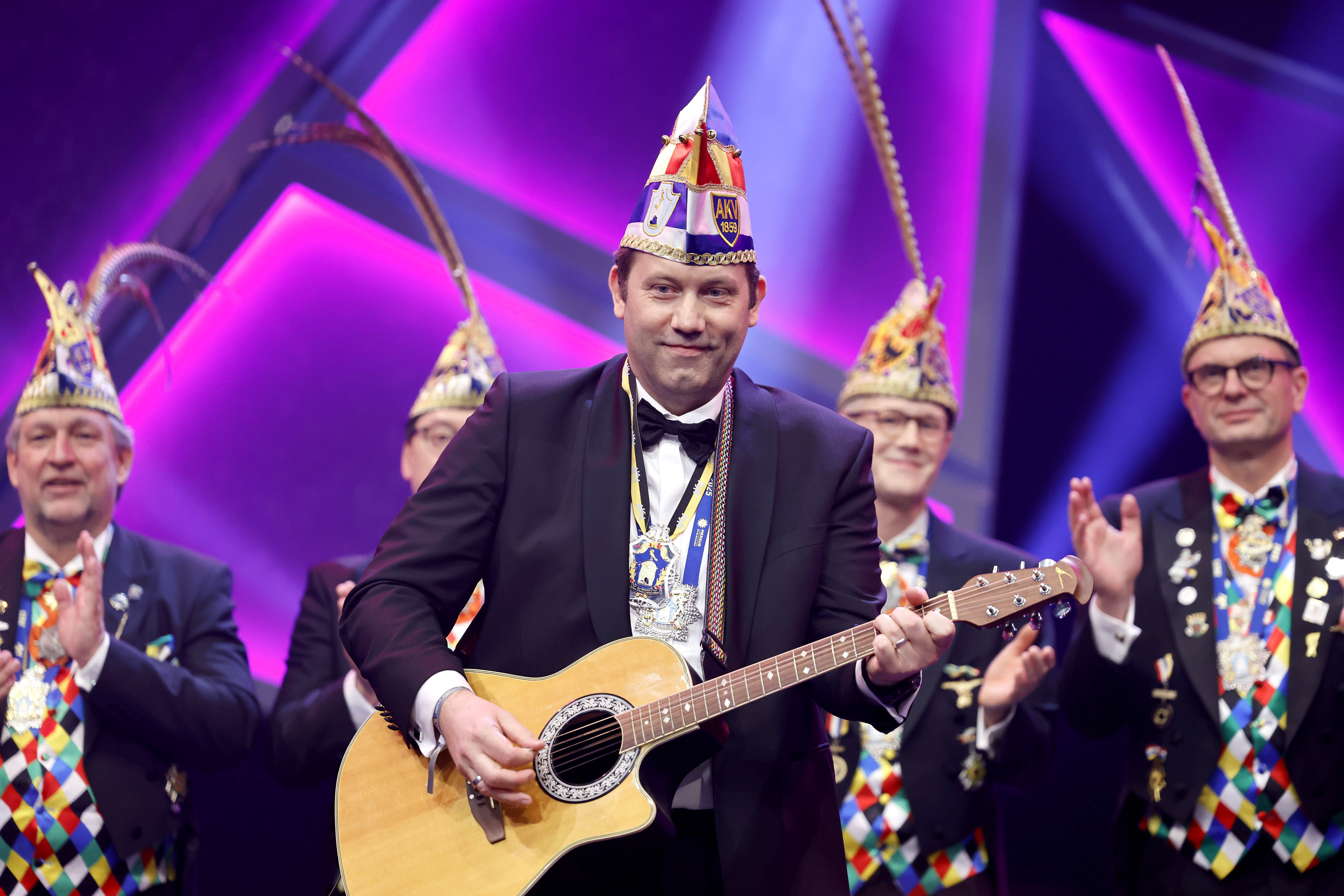 Der SPD-Vorsitzende Lars Klingbeil steht beim Aachener Karneval mit Gitarre und „Rittermütze“ auf der Bühne.