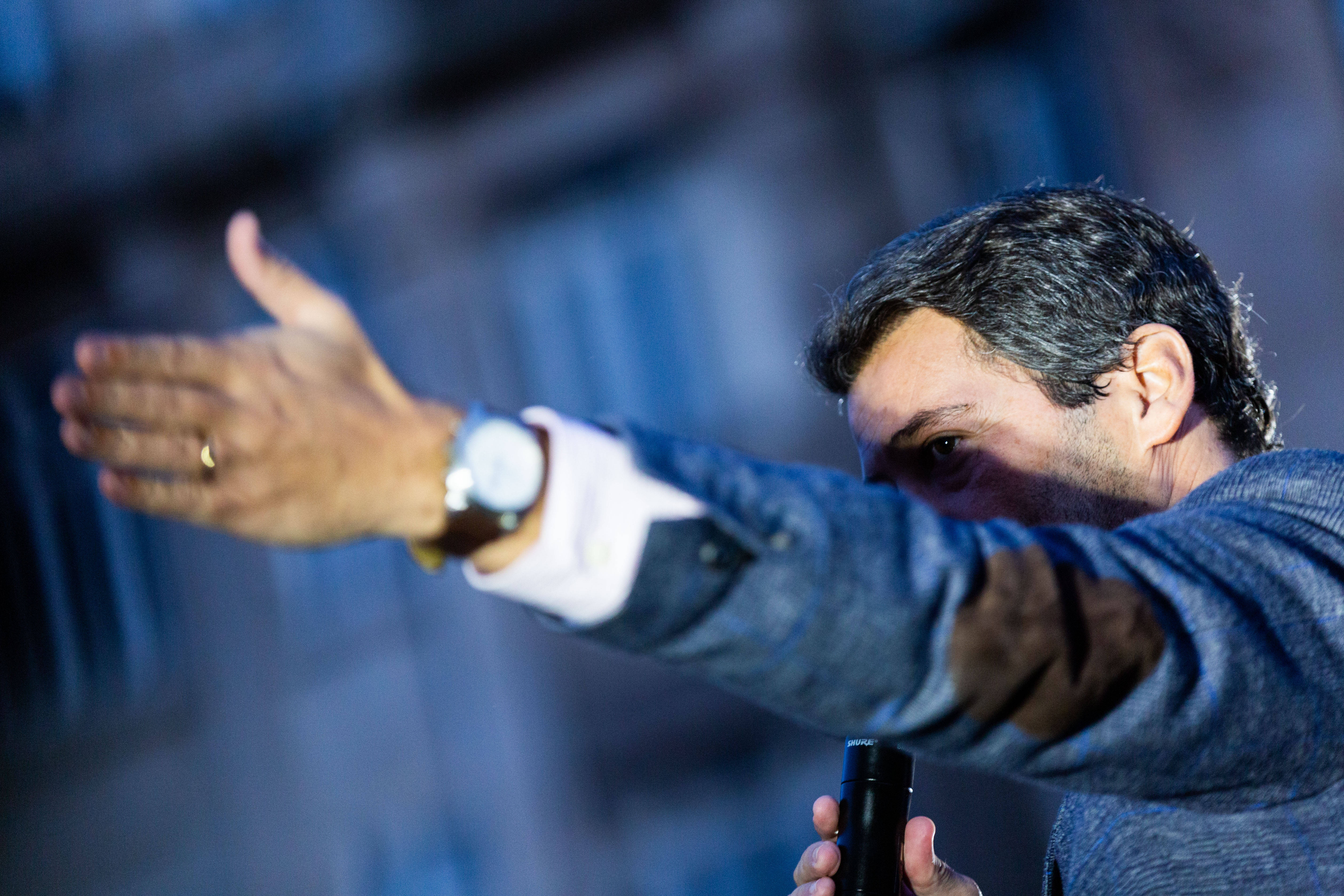Der Rechtspopulist Andre Ventura steht auf einer Bühne in der nordportugiesischen Stadt Porto. Er gestikuliert mit ausgestrecktem linken Arm, der Ärmel seines blauen Sakkos, seine Armbanduhr und sein Ehering sind zu sehen.