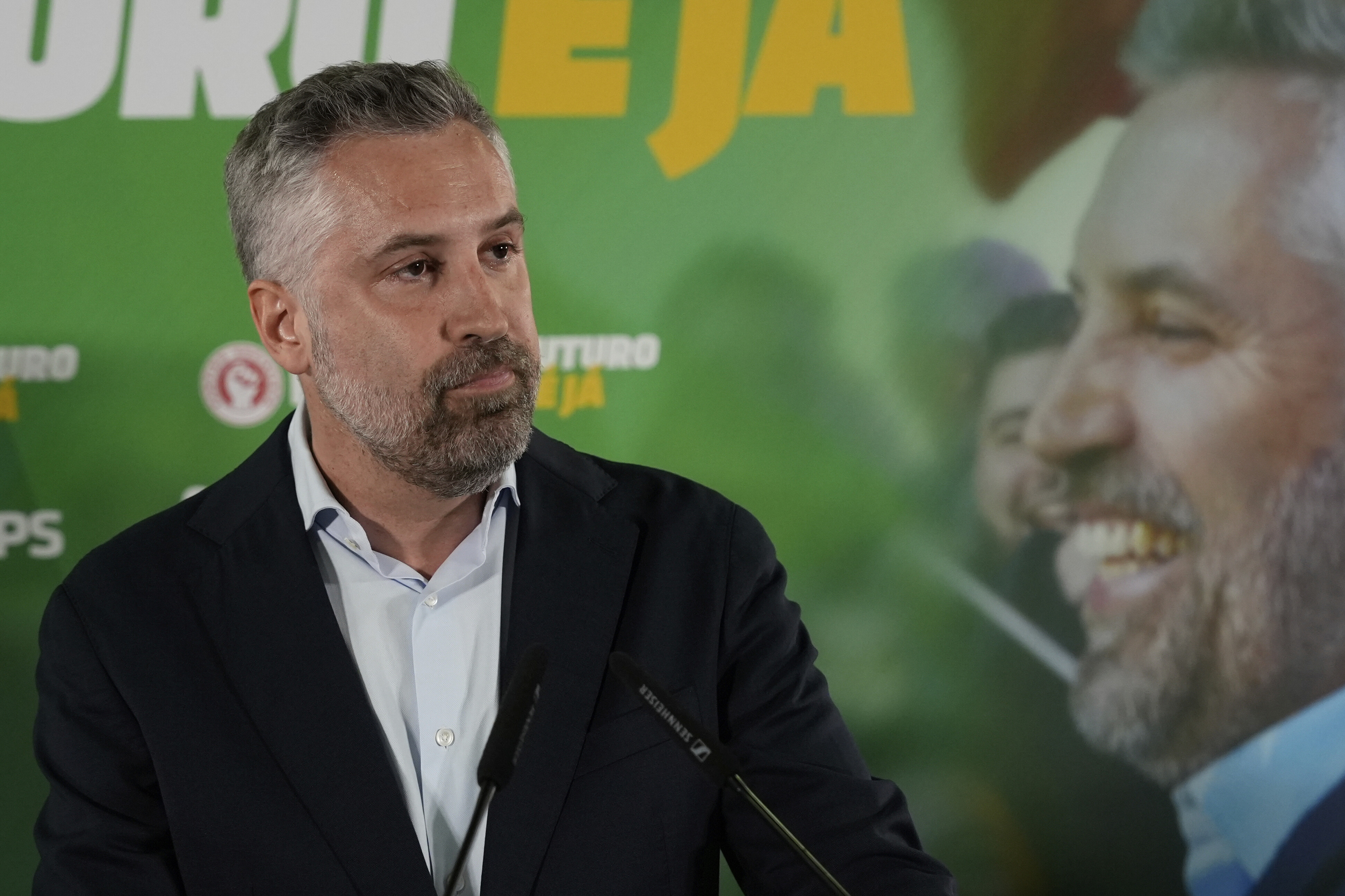 Der Spitzenkandidat der portugiesischen sozialistischen Partei Pedro Nuno Santos steht mit traurigem Gesichtsausdruck auf einer Bühne vor zwei Mikrofonen.