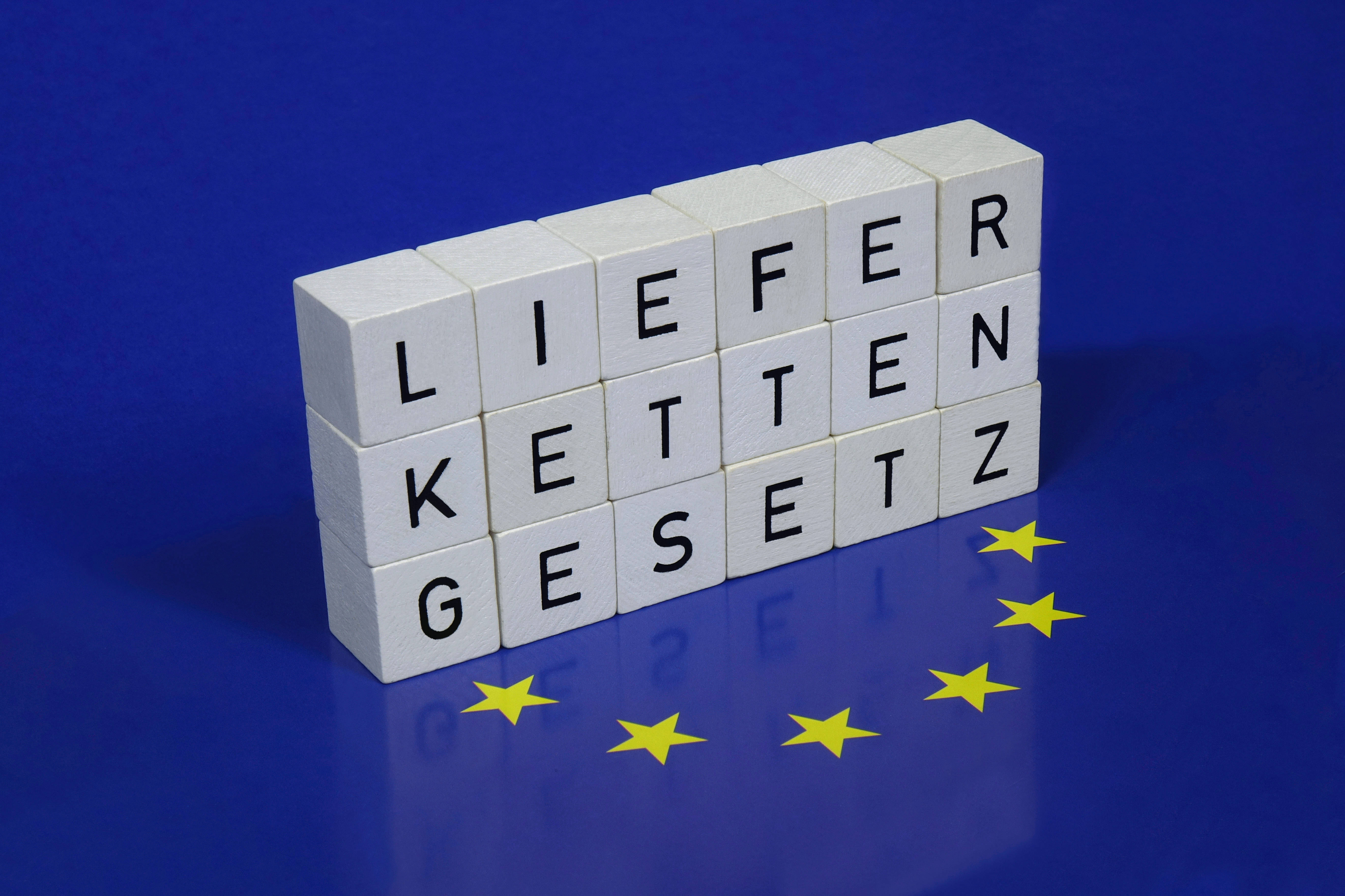Aufschrift Lieferkettengesetz auf europäischer Flagge