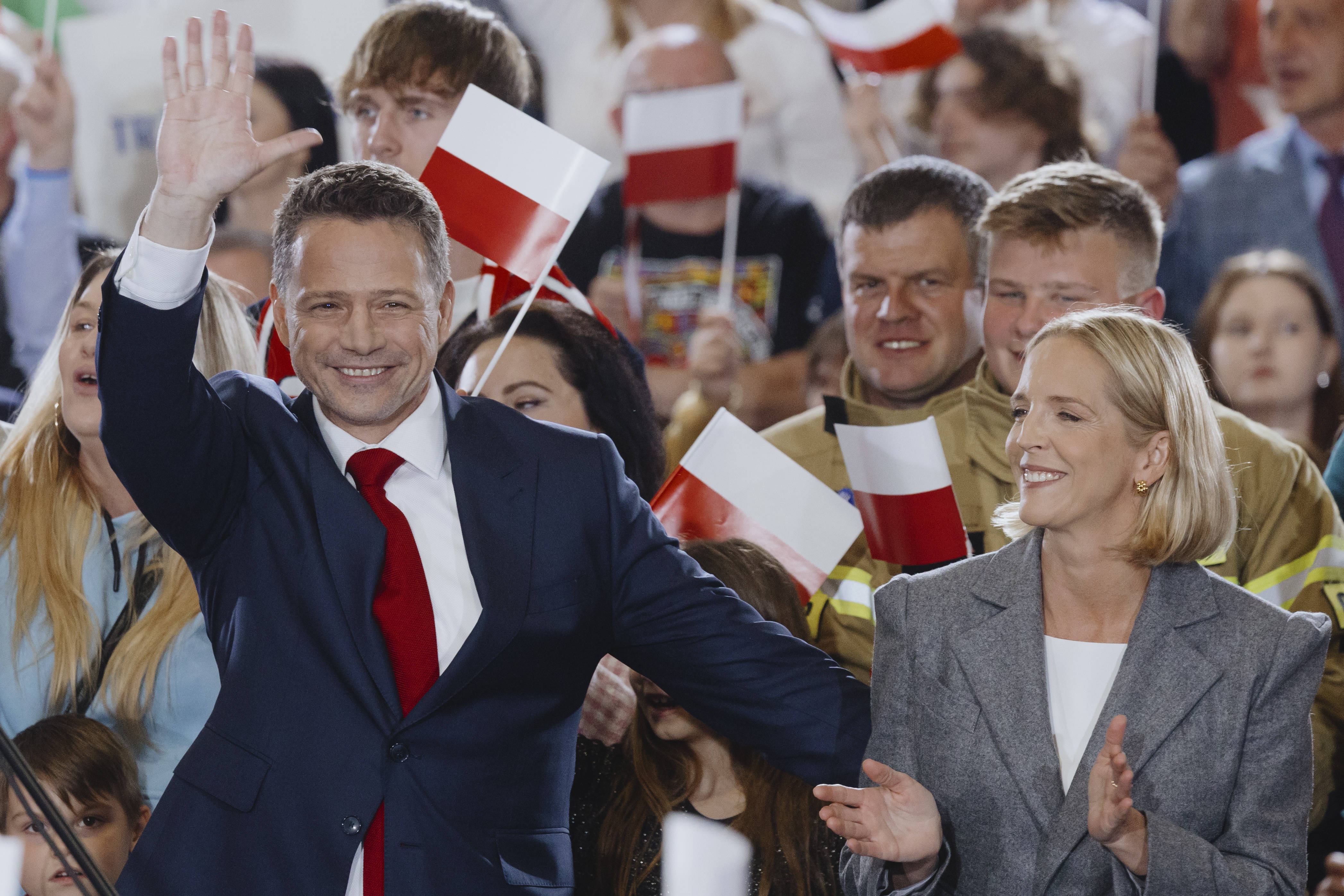 Der amtierende polnische Staatspräsident Rafal Trzaskowski und seine Frau winken in die applaudierende Menge.