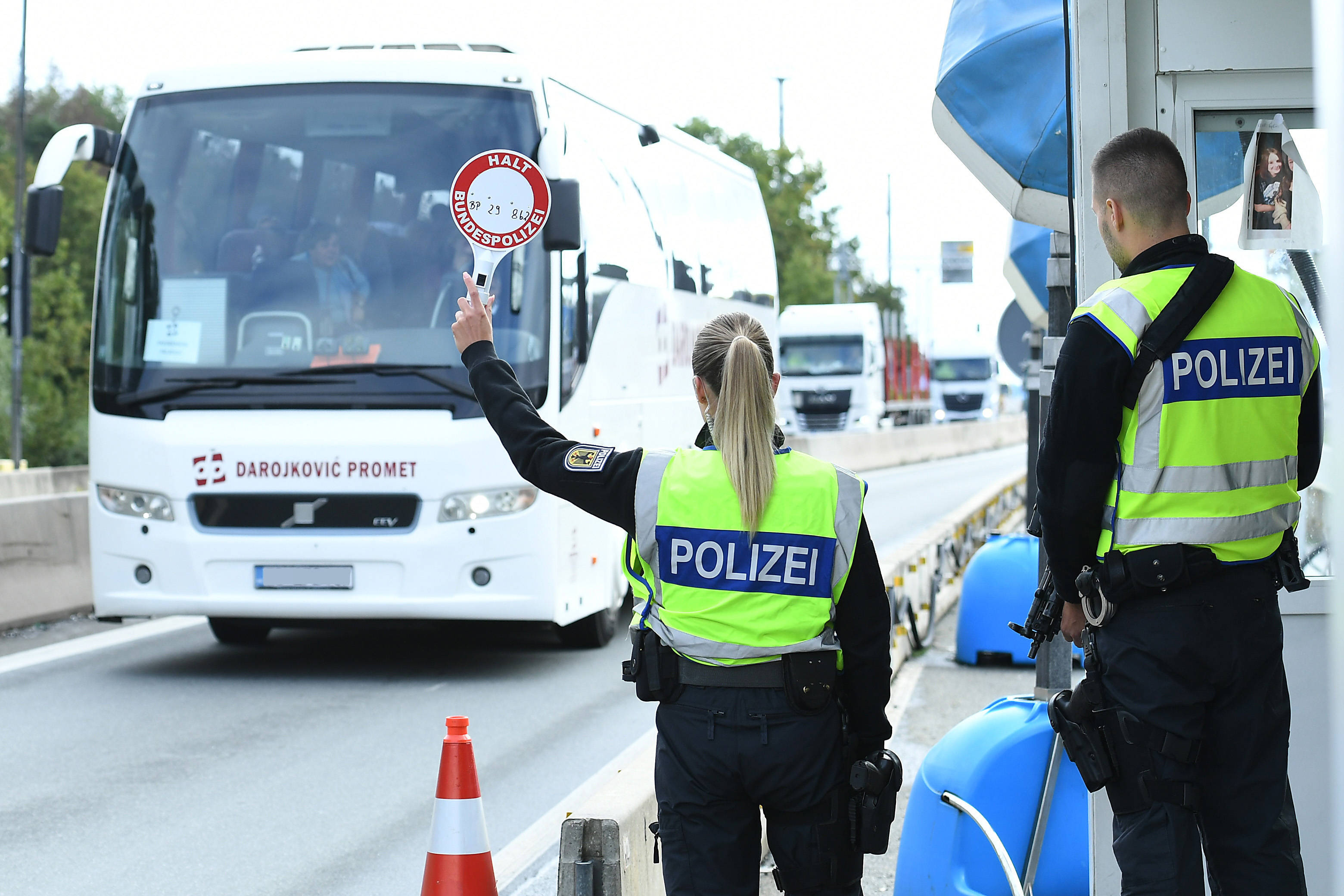 Zwei Polizisten halten an der deutsch-österreichischen Grenze einen Reisebus an.
