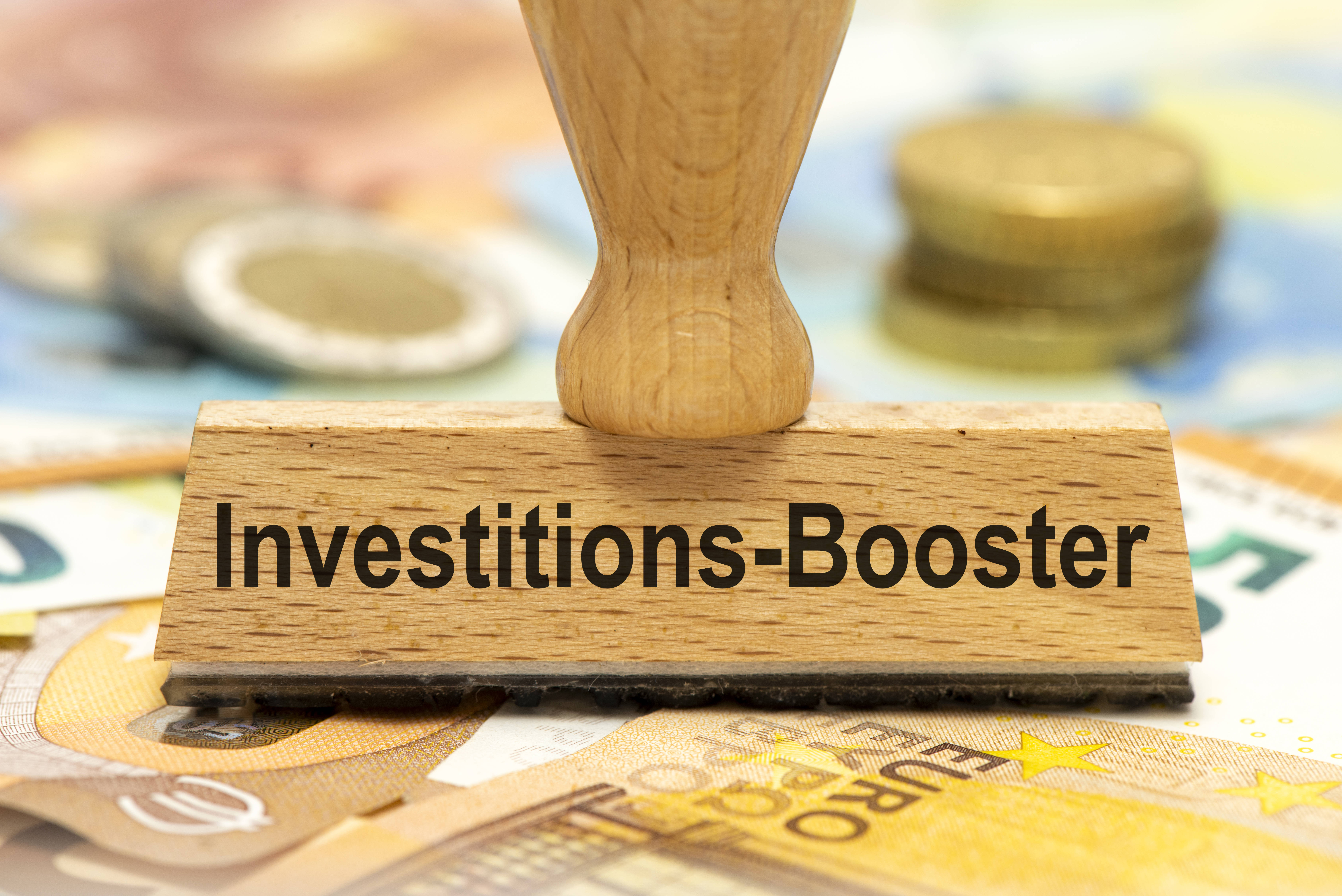 Ein Stempel mit der Aufschrift "Investition-Booster" steht auf Euro-Scheinen.