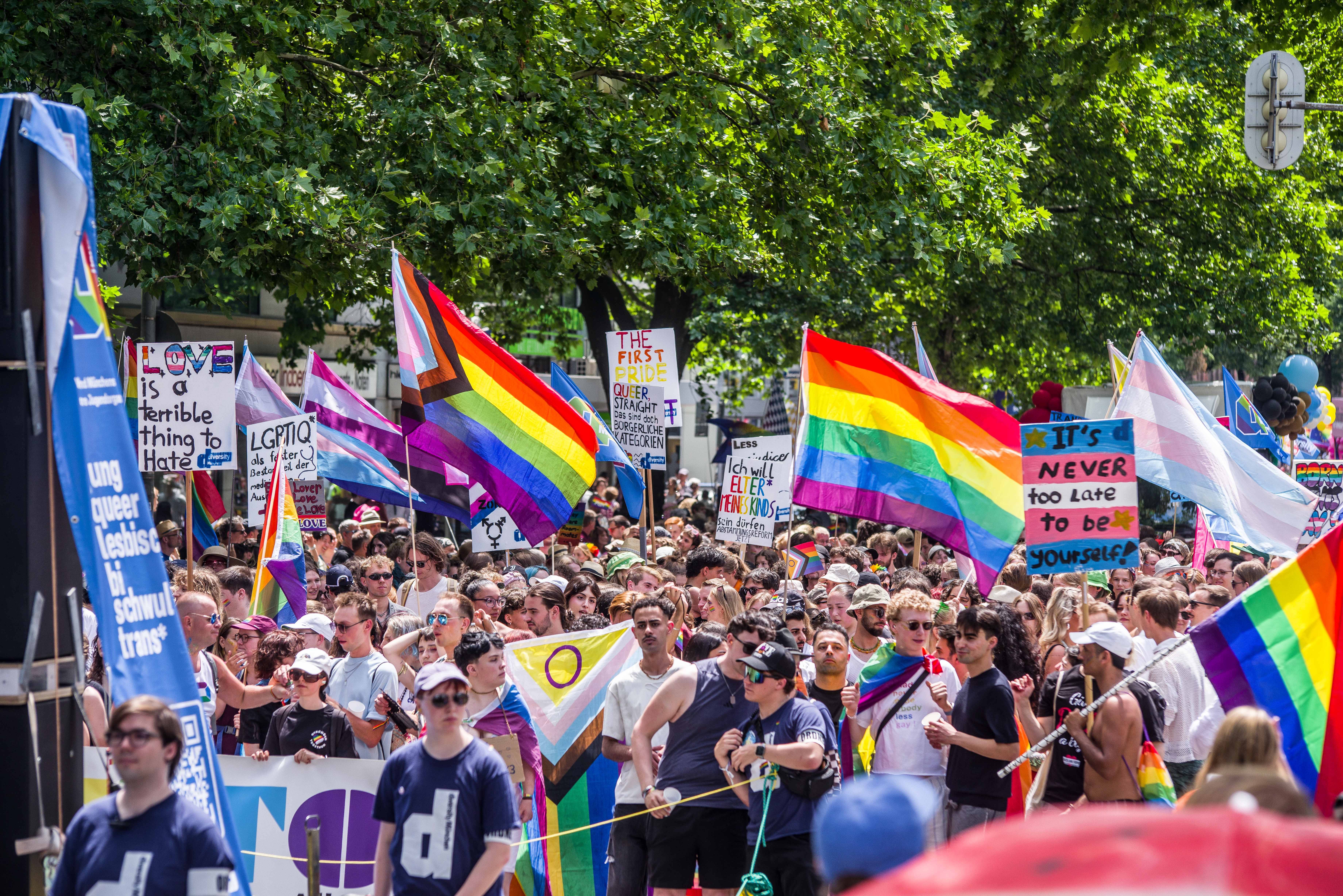 CSD-Parade in München: Viele Menschen mit bunten Schildern und Regenbogenflaggen.
