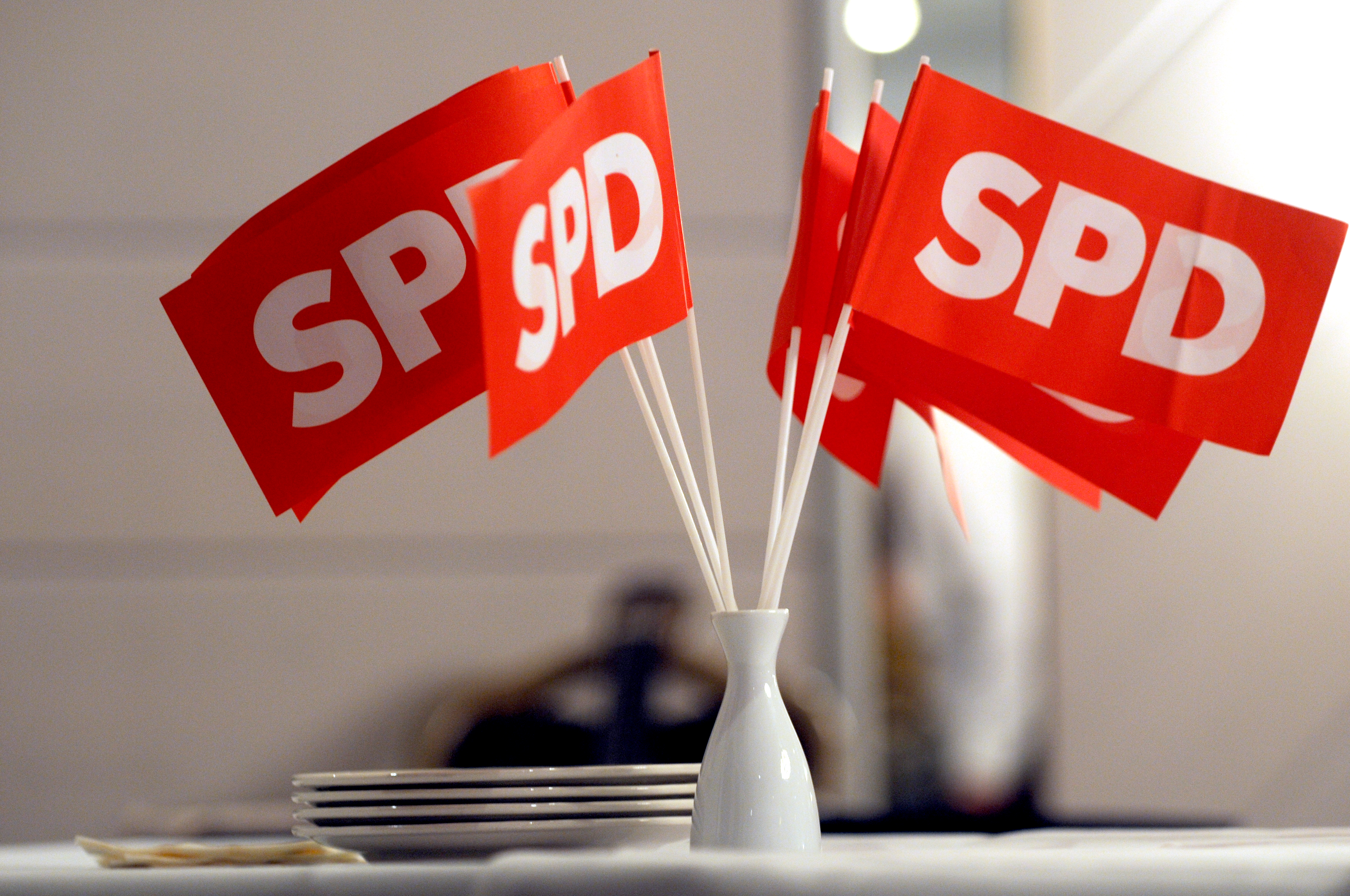 Rote SPD-Fähnchen stehen in einer weißen Blumenvase.