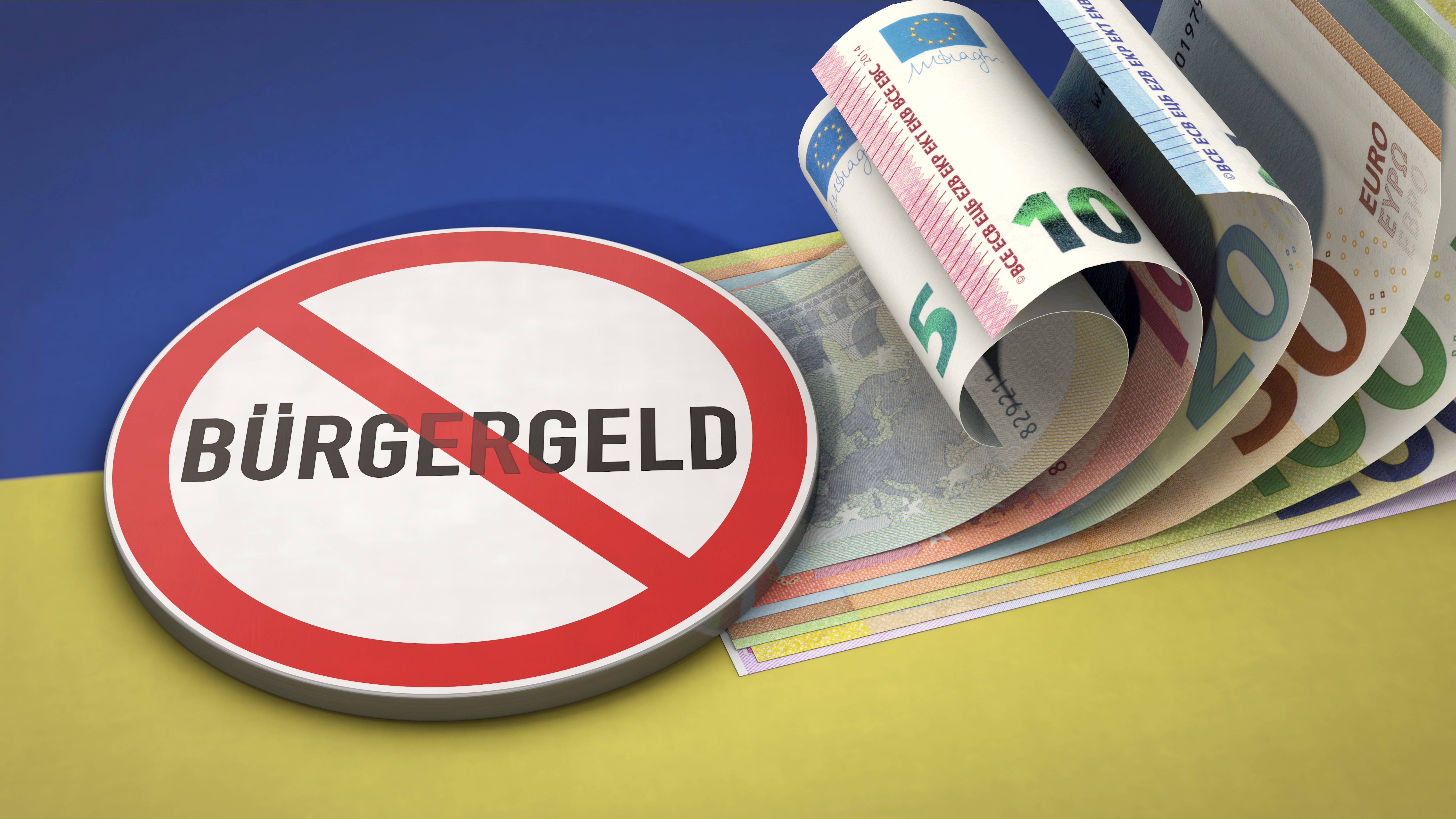 Fotomontage: Warnschild, auf der das Wort "Bürgergeld" durchgestrichen ist mit einem Bündel Euro-Scheine auf einer ukrainischen Fahne