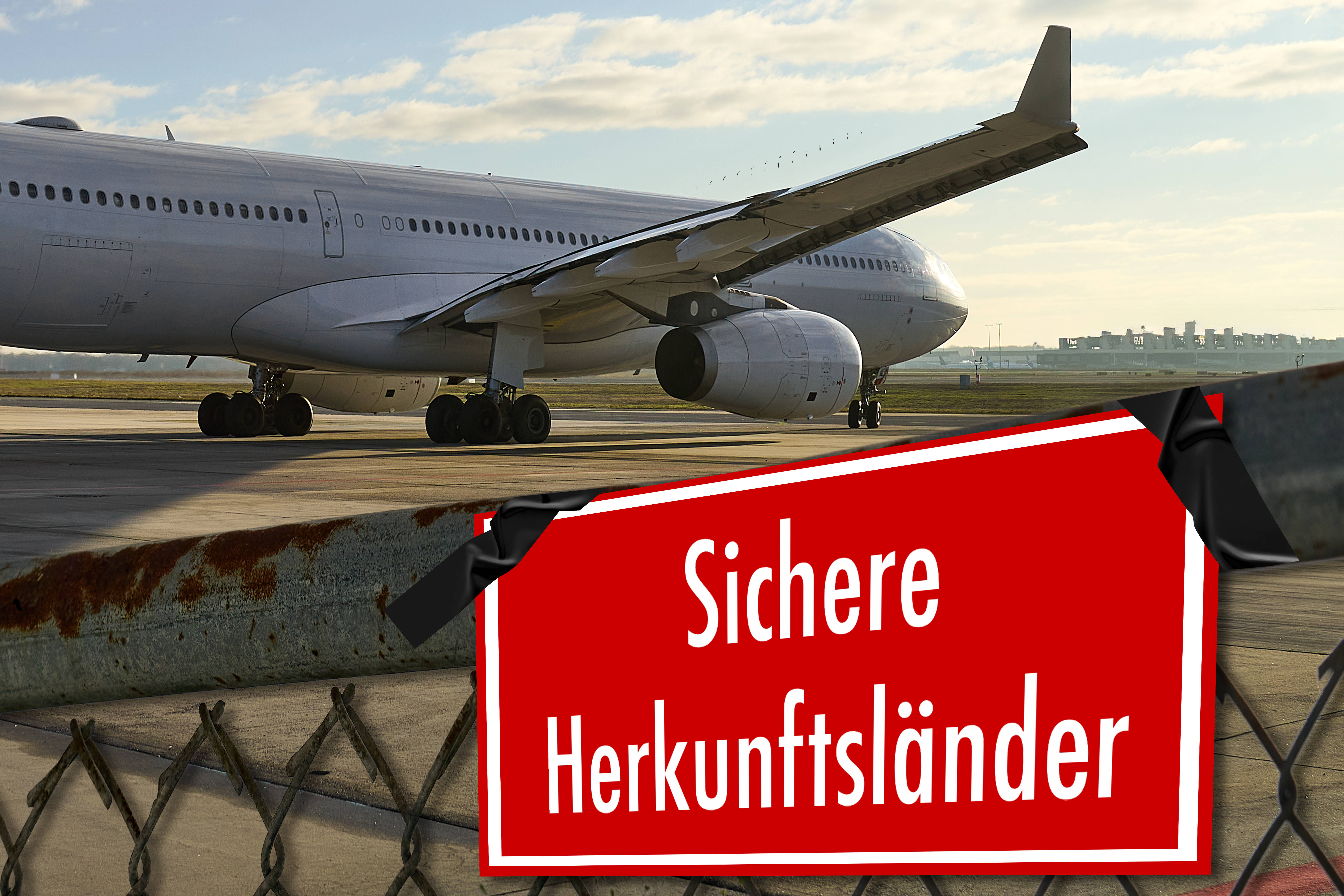 Rotes Schild mit weißer Aufschrift "Sichere Herkunftsländer", im Hintergrund ein Flugzeug