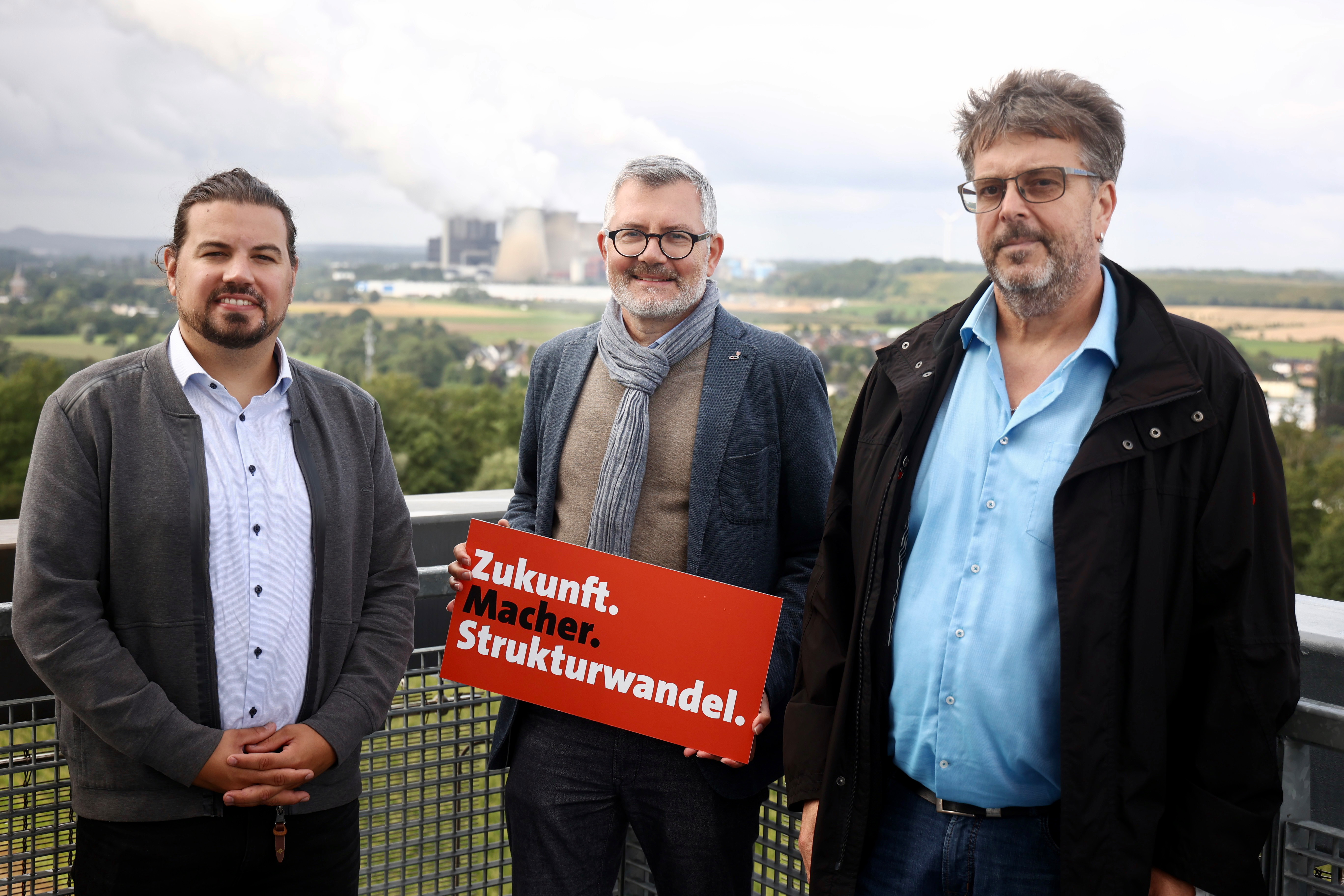 Dietmar Nietan (M.) im Gespräch mit dem Vorsitzenden des Gesamtbetriebsrates RWE Power, Harald Louis,(l.) und Matthias Dürbaum, Betriebsratsvorsitzender vom Tagebau Hambach,(r.) bei strömendem Regen auf dem „Indemann“.