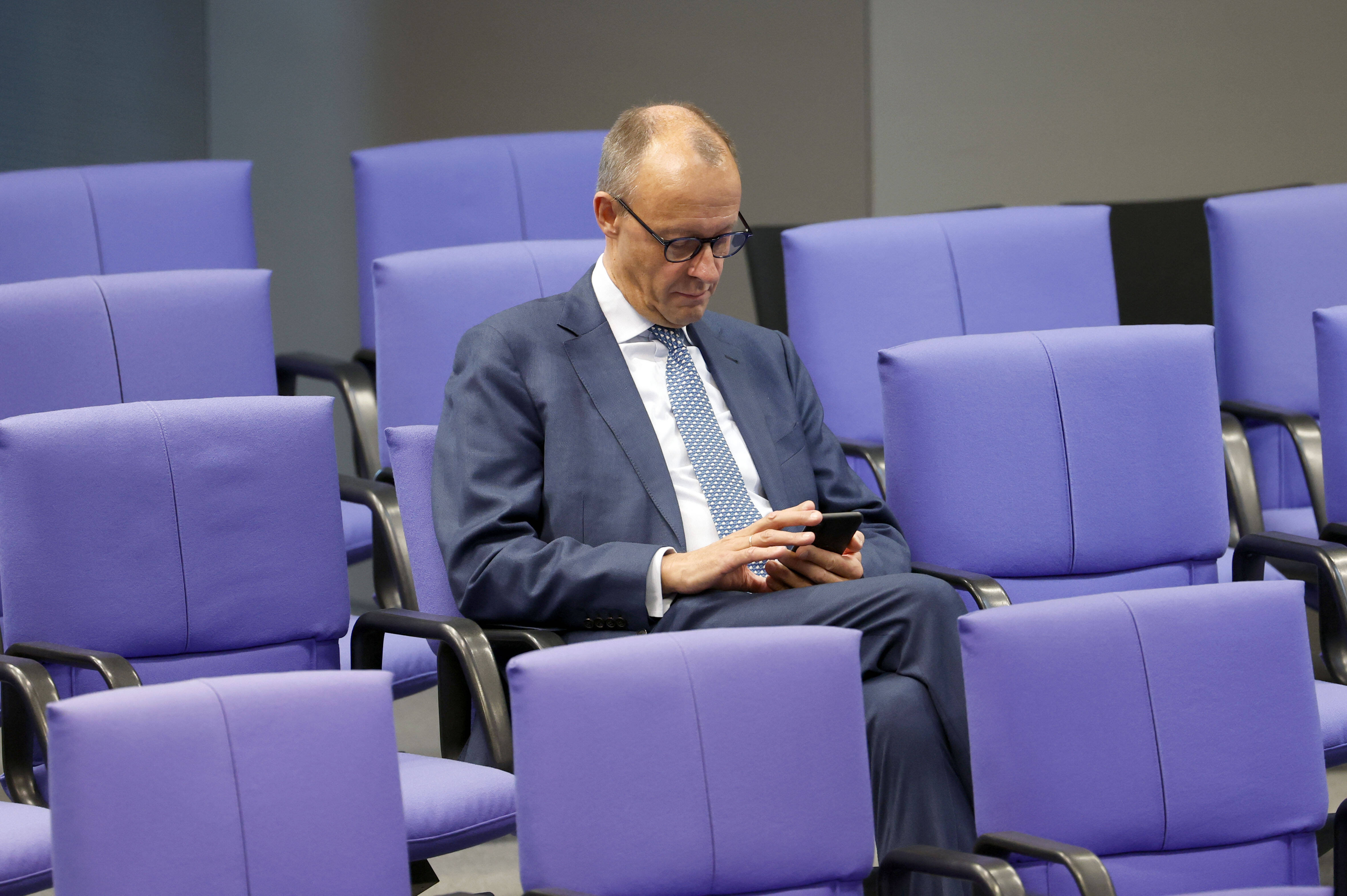 Friedrich Merz schaut auf sein Handy.