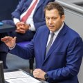 Lars Klingbeil mit erhobener Hand am Redepult im Bundestag