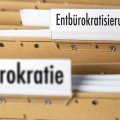 Aktenordner mit den Vermerken "Bürokratie" im Vorder- und "Entbürokratisierung" im Hintergrund
