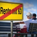 Bildmontage: Ein Ortsausgang-Schild mit dem durchgestrichenen Schriftzug "Rente mit 63" und im Hintergrund einem Rentner-Paar auf einer Parkbank